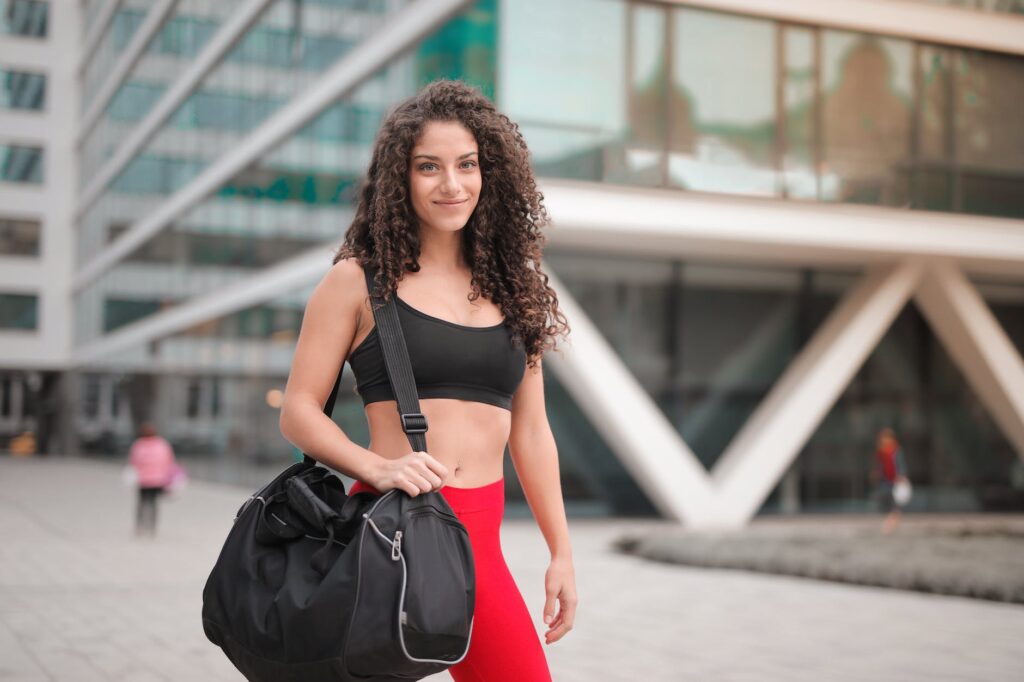 selective focus photo of smiling woman in active wear carrying gym bag