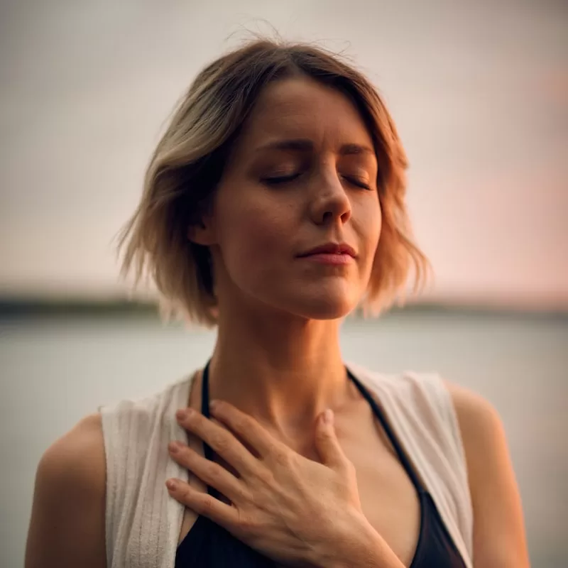 woman in white vest and black bikini with hand on chest